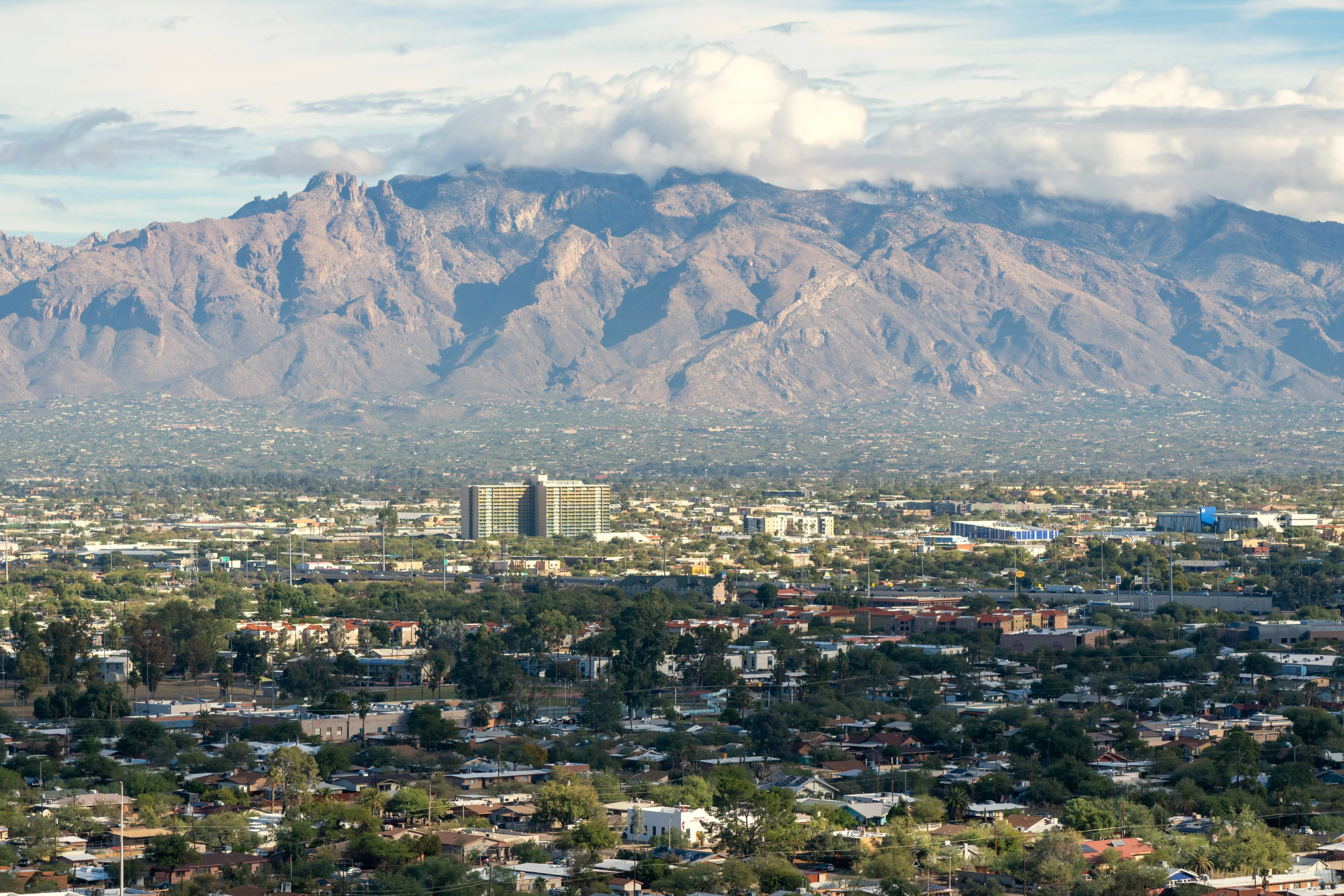 Tucson neighbourhoods stretching toward the Santa Catalina Mountains under drifting clouds